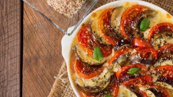 UN GRATIN D'AUBERGINES ET DE VIANDE HACHÉE FINEMENT AROMATISÉ ET GRATINÉ AU FOUR.