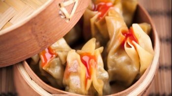 Ravioles de porc aromatisées à la coriandre, à la citronelle et au gingembre, cuites à la vapeur et accompagnées d'une sauce tomate pimentée.